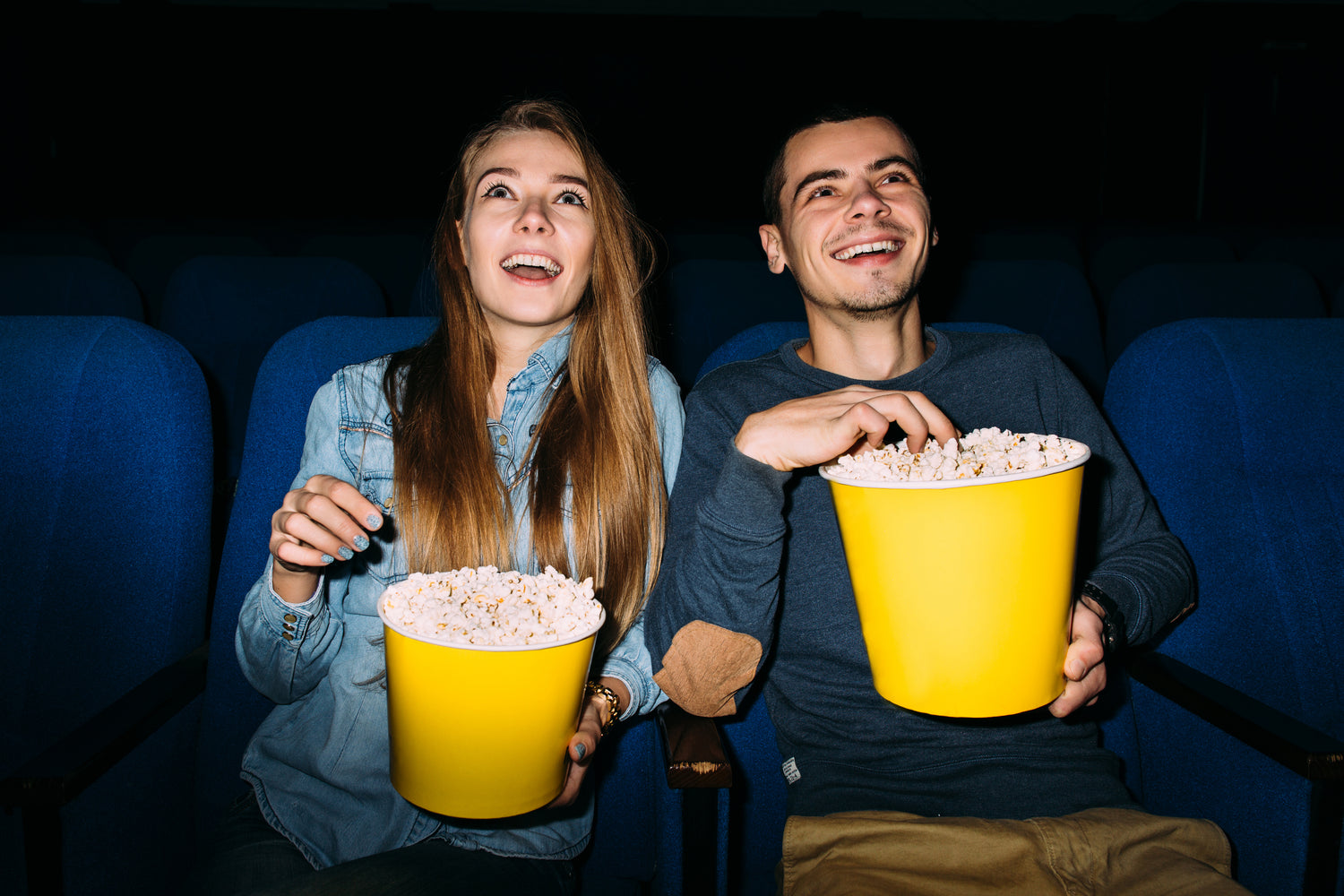 Deux amis dégustant du popcorn devant un film projeté avec un vidéoprojecteur portable 4K pour une ambiance cinéma.